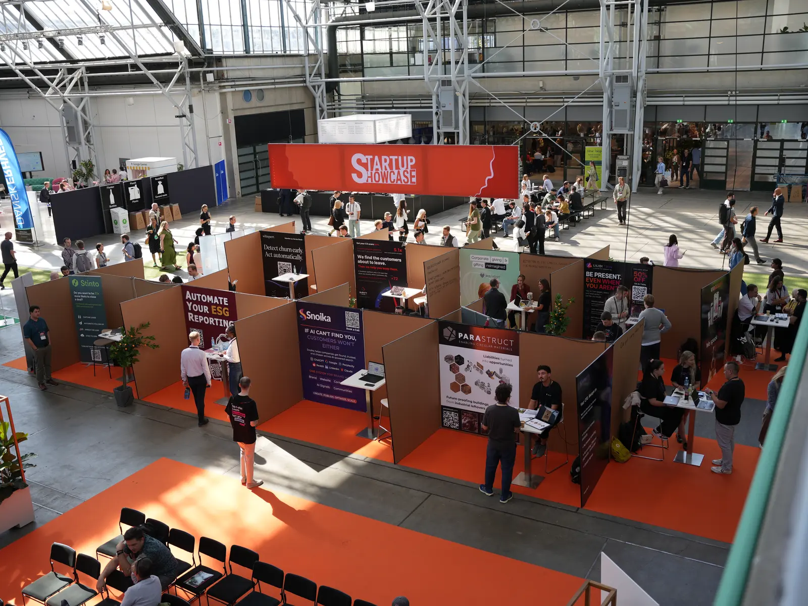 TechBBQ 2026 Startup Showcase floor in Copenhagen seen from the balcony above, with orange walkways between startup booths.